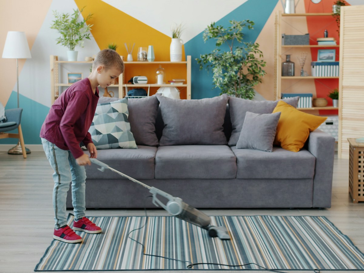 Young girl vacuuming a striped rug in a living room
